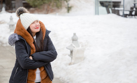 An Asian woman and her family are enjoying a winter snowy vacation and doing family activities in...