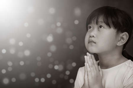Asian face Child praying and worship to GOD Using hands to pray in religious beliefs and worship christian in the church or in general locations in  White and Black backgroundの写真素材