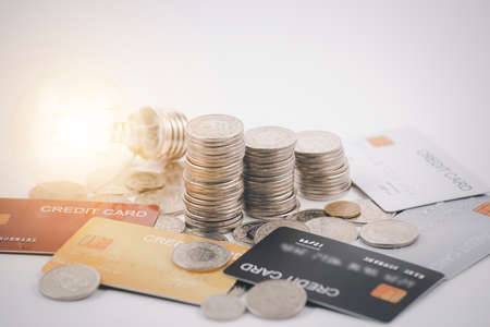 Coins with credit card and light bulb on the white background for finance and banking , Saving ideas and investment budget, Creative ideas concept of saving moneyの写真素材
