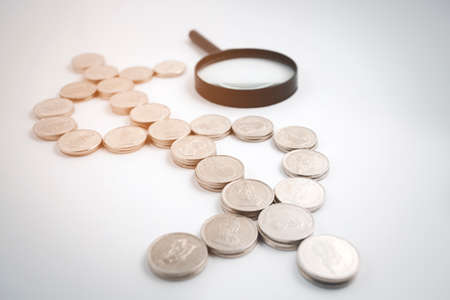 Coins stack close-up with magnifying glass on the white background, Money spending planning, and investment budget, Business saving money concept, Copy spaceの写真素材