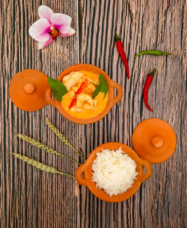 Chicken Panang Curry with Rice is Thai food sauce curry and basil leaf and coconut milk put on Terracotta pot on a banana leaf in wooden backgroundの写真素材