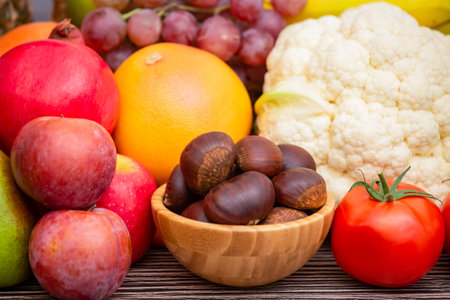 Group vegetables and Fruits Apples, grapes, oranges, and bananas in the wooden basket with carrots, tomatoes, guava, chili, eggplant, and salad on the table.の写真素材