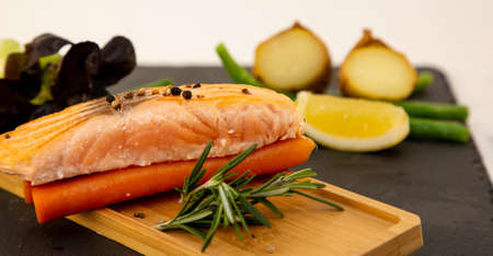 Grilled fresh salmon steak with roasted green beans, baked potato, lemon slices and salad vegetables is a healthy diet for dieting on a wooden plate.の写真素材