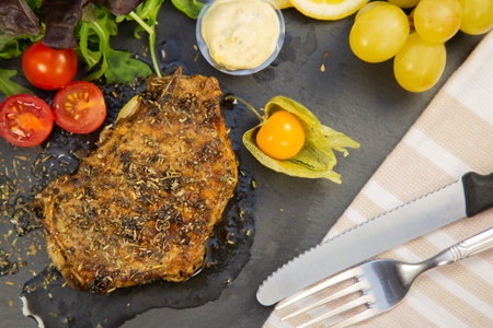 Dinner Prepare Pork steak grilled in olive oil and herbs is a popular food in Europe. Salads with lemons, grapes, tomatoes are healthy foods for diet in the stone tray view.の写真素材