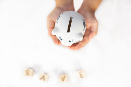 White Piggy bank in  Hand family and wood word save money in the future for family background, Saving ideas  and investment budget, Business saving money concept, Copy spaceの写真素材