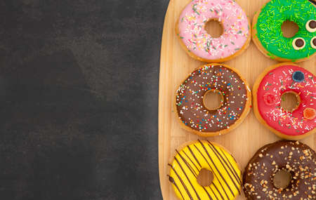 Dessert, Donuts, chocolate and strawberry circles, sugar and cream on Donuts and hot coffee cups, preparation for a break or party on the wooden table background.の写真素材