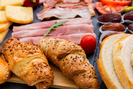 Breakfast on the table. Croissant bread, Croissant cereal, Bacon, ham, cheese, lettuce, beans, corn...