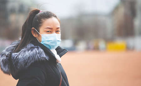 The image face of a young Asian woman wearing a mask to prevent germs, toxic fumes, and dust. Prevention of bacterial infection in the air around the streets and gardens.の写真素材