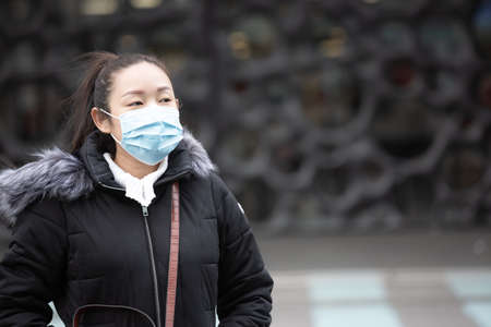 The image face of a young Asian woman wearing a mask to prevent germs, toxic fumes, and dust. Prevention of bacterial infection in the air around the streets and gardens.の写真素材
