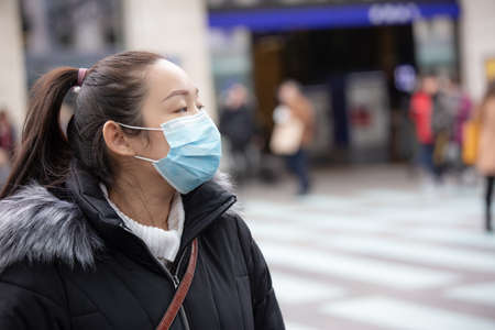 The image face of a young Asian woman wearing a mask to prevent germs, toxic fumes, and dust. Prevention of bacterial infection in the air around the streets and gardens.の写真素材