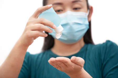 The image face of a young Asian woman washes hand gel sanitizing and wearing a mask to prevent germs, toxic fumes, and dust. Prevention of bacterial infection in the air in a white backgroundの写真素材