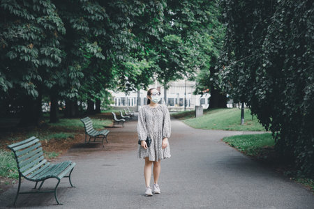 Asian beautiful woman wearing a mask to protect against COVID-19 And air viruses Walking in the park...