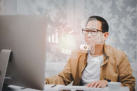 Asian man in casual clothing using a laptop communicates on the internet with the customer at  kitchen table at home. concept work from home.の写真素材