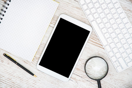 White Tablet With Blank Screen, laptop and accessories and office stuff On Wooden Desk With...