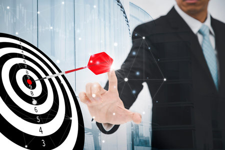 Businessman touching a darts aiming at the Bullseye is a target in black background - focus on...