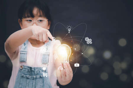 Asian Little girl touch the light bulb in graph Screen Icon of media screen,Technology Process System Business concept.の写真素材