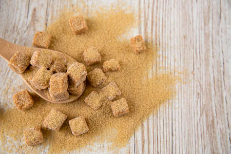 Brown sugar in a square cup and wooden spoon on a wooden table, healthy sugar is used for cooking food or desserts.の写真素材