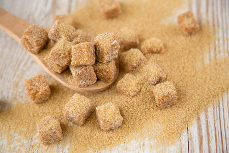 Brown sugar in a square cup and wooden spoon on a wooden table, healthy sugar is used for cooking food or desserts.の写真素材