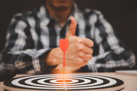 Targeting the business concept, Businessman showing thumbs up and look at red arrow dart to virtual target dart board,Executive marketing, investment goal and target for business investment concept.の写真素材