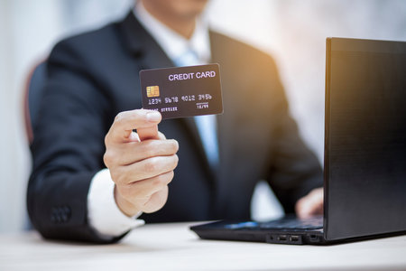 Businessman holding credit card for makes a purchase on the Internet on the laptop computer with...