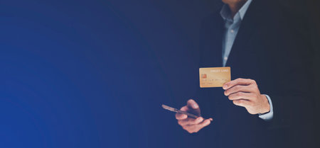 businessman is holding credit card and using mobile phone. Online shopping concept,banking and online shopping at the home.Close up.の写真素材