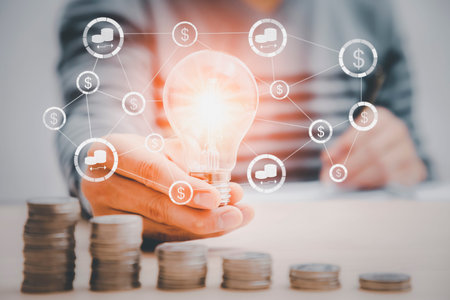 thinking and creative concept, businessman hand holding light bulb with coins stacking on desk.saving energy and money,The idea of ââinspiration from online technology.innovation idea concept.の写真素材