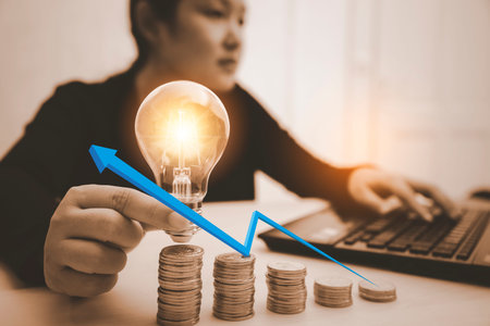 Woman hand holding light bulb with white arrow  and working with computer on the desk, Creativity and innovation are keys to success.Concept of new idea and innovation with Brain and light bulbsの写真素材
