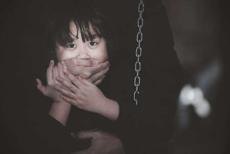 Child abduction concept, defense or safety and Children kidnapping in home or playground, Scared young girl with an adult man's hand covering her mouthの写真素材