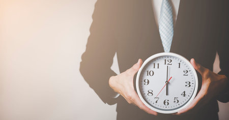 Concept of saving time, Businessman holding a clock against time 6 am in the morning on the White...