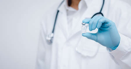 Close Up man doctor or scientist in uniform wearing face mask with a stethoscope holding vaccine, Healthcare And Medical concept, vaccine Concept fight against virusの写真素材