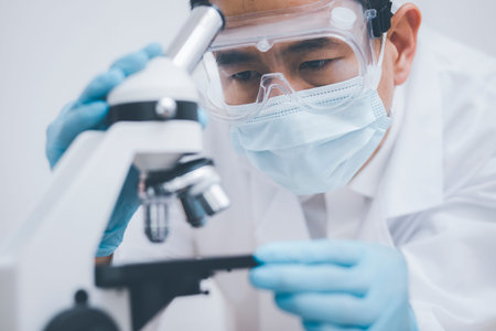 biochemical research scientist working with microscope for , laboratory glassware containing...