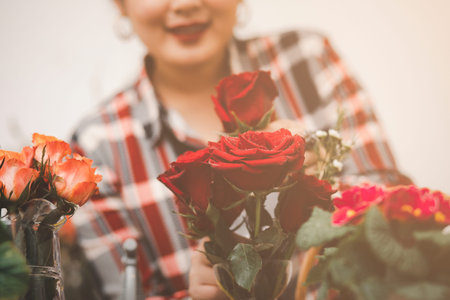 Online home flower arrangement concept, Woman Preparing to trim red and pink roses and beautiful flower arrangements in the home, flower arrangements with vase for gift-giving for Valentine's Dayの写真素材