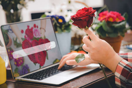 Online home flower arrangement concept, asian woman Smiling florist record video broadcast or course on smartphone or computer, compose arrange floral decorations,online flower shopの写真素材