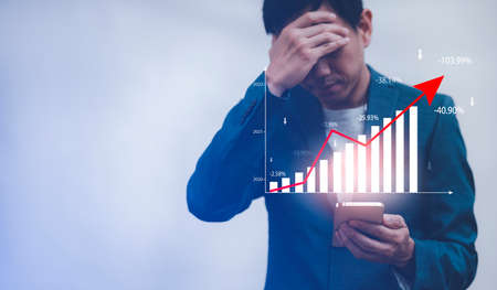 Business losses on the stock market chart concept, Business hand hold laptop market chart and Red arrows fall to the ground, indicating the economic recession that will occur in 2021の写真素材