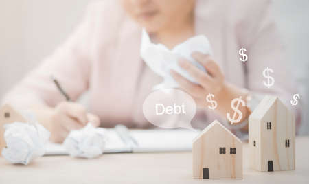 Businesswoman hand write note on paper with mini wood house model from model on wood table, Planning buy Real Estate, Planning to buy property. concept of Choose the best.の写真素材