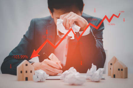 Concept of falling real estate market, down arrow and wooden house. The concept of falling property prices. Lower housing prices. Low rent, Decline in the value of the property. Low utility prices.の写真素材