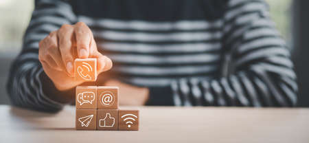 communication and technology concept , Hand putting wooden block cube symbol telephone, email, address. Website page contact us or e-mail marketing, Contact us in customer support conceptの写真素材