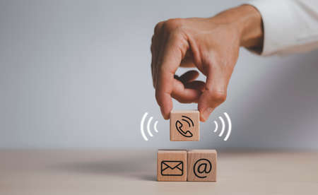 communication and technology concept , Hand putting wooden block cube symbol telephone, email, address. Website page contact us or e-mail marketing, Contact us in customer support conceptの写真素材