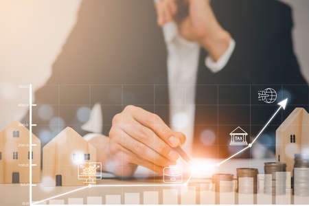 Hand touch arrows graph business investment market and stacked coin with mini wood house model from the model on table, Planning buy Real Estate, Planning to buy property. concept of Choose the best,の写真素材
