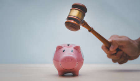 Old wood Judge hammer with Happy Pink piggy Bank in close-up and coins stack the table wood background, Used for adjudication and Justice,Bank account arrest conceptの写真素材