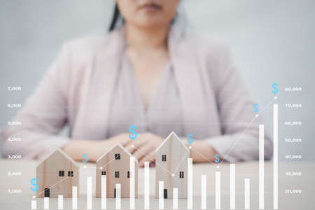 Businesswoman and mini wood house model and wood cubes of business from model on wood table, Planning buy Real Estate, Planning to buy property. Home insurance and security ideas concept.の写真素材