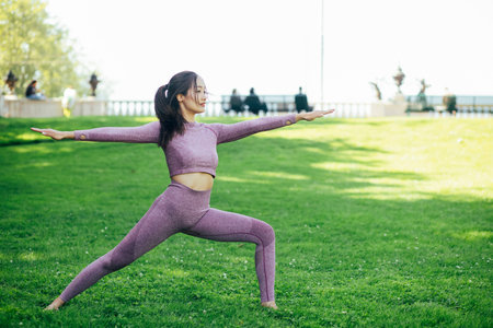 Young Asian woman doing yoga fitness exercises in the nature park, Exercise for health or warm-up...
