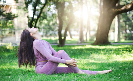 Young Asian woman doing yoga fitness exercises in the nature park, Exercise for health or warm-up body, fresh air, or Oxygen in the green tree in the park in sunlight.の写真素材