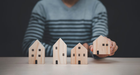 Man hand choosing mini wood house model from model on wood table, Planning buy Real Estate, Planning...