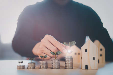 Close up of male hand stacking coins and Trees growing on coin in dark background ,Business Finance and Money, plant growing up on coins and investment budget, saving money investment.conceptの写真素材