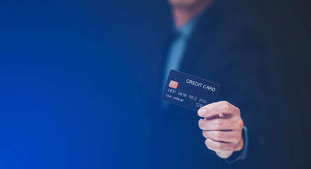 businessman is holding credit card and using mobile phone. Online shopping concept,banking and online shopping at the home.Close up.の写真素材