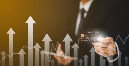 Businessman hand holding Model credit card with arrow graph of market stock and using mobile phone....