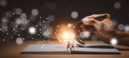 Thinking and creative concept, Light bulb on the Book and light bulb style bokeh vintage dark background,Concept The idea of reading books, knowledge, and searching for new ideas.の写真素材