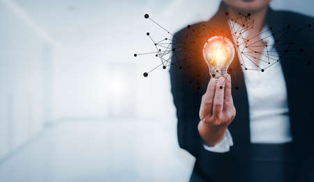 Businesswoman hand holding light bulb with line connect and working on the desk, Creativity and innovation are keys to success.Concept of new idea and innovation with energy and power , working.の写真素材