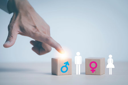 concept equality and differences between men and women, Hand touch wooden cube with male icon on top...